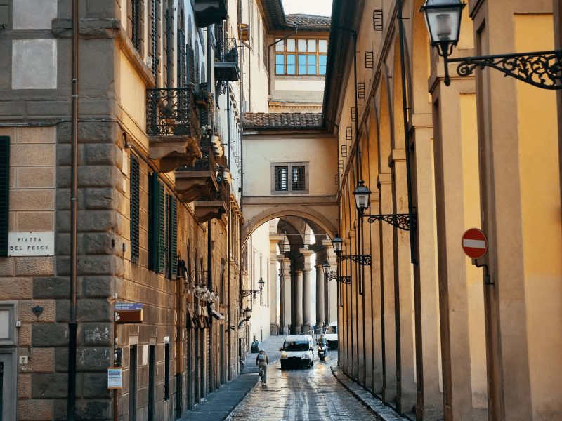 a street in downtown florence with the sign piazza del pesce and historic buildings