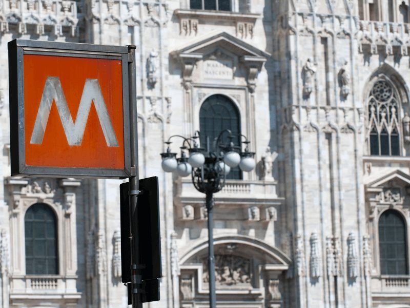 milan metro sign in front of the duomo architecture in the background