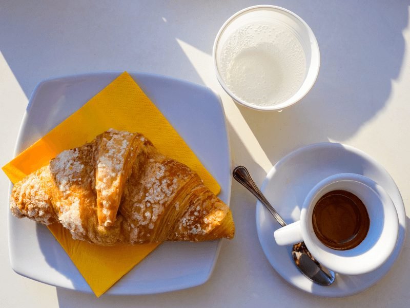 a cornetto (italian version of a croissant) served with espresso and water