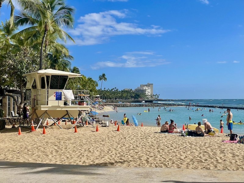 people on the beach and a lifeguard tower on waikiki beach