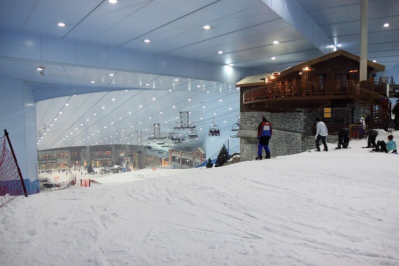 people skiing indoors at ski dubai indoor ski and snowboarding area with a faux ski chalet