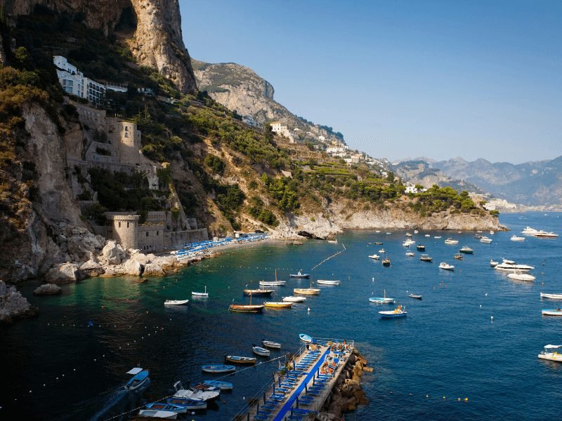 Lots of small boats in the marina of Conca dei Marini, a charming Amalfi coast town with beautiful coastal buildings and a small beach