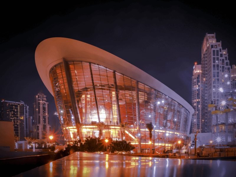 Dubai opera house lit up at night with unique architecture