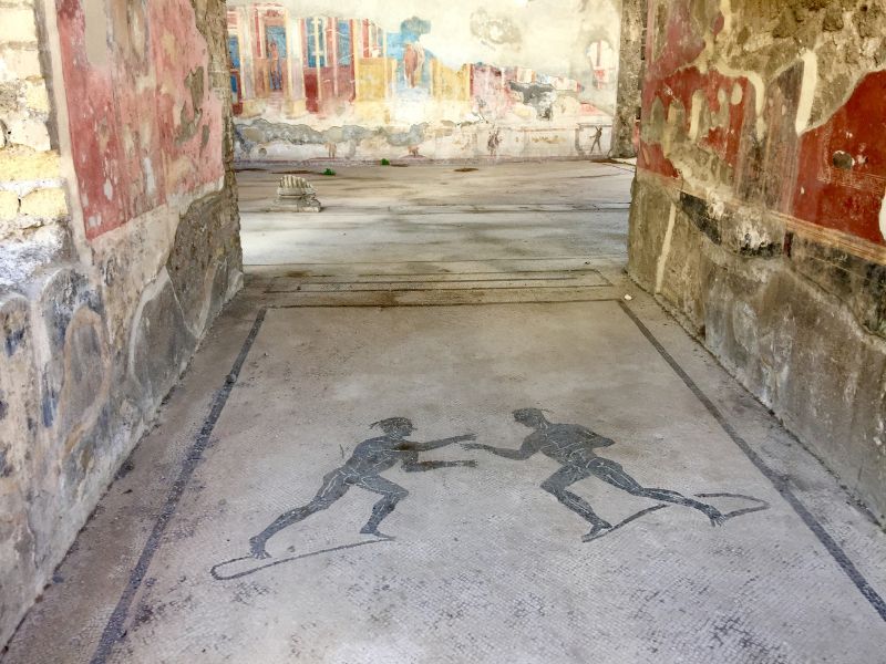 floor mosaic of people fighting in Pompeii roman ruins