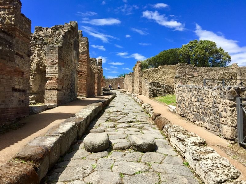 two stones in the middle of a cobblestone road in Pompeii which makes this site hard to access for those with disabilities like mobility limitations