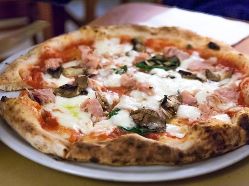a real neopolitan pizza cut into slices with ham and mushroom and spinach