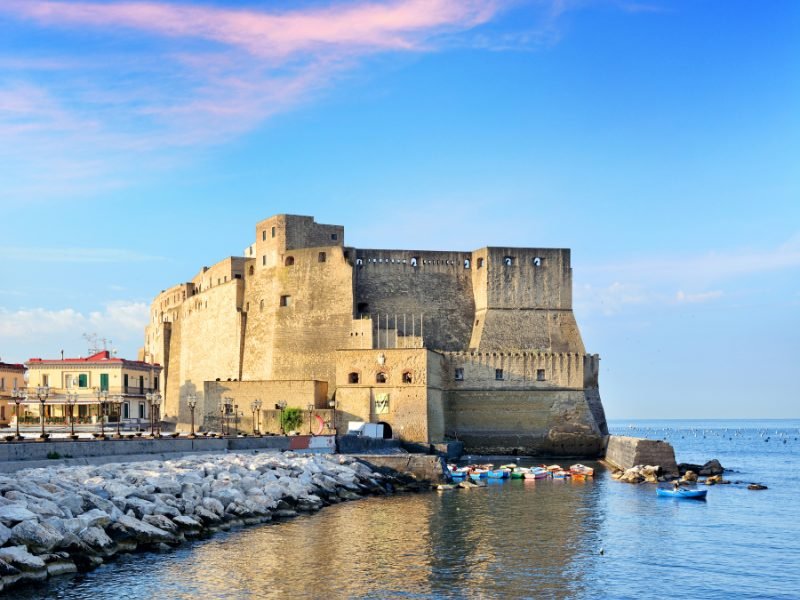 castle on the water seen with sunset colored clouds