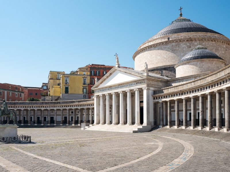 detail of a square in naples italy with pillars and a statue and a small church