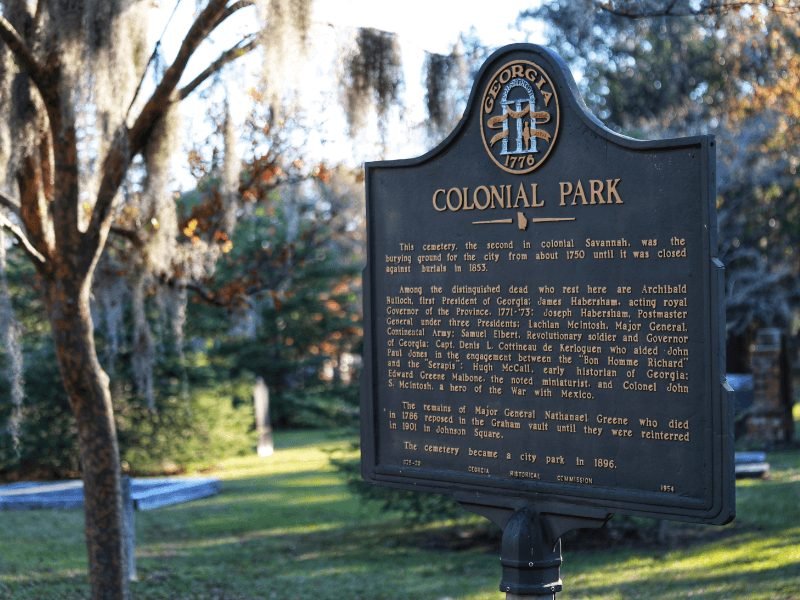 sign for colonial park cemetery with trees and gravestones in the background