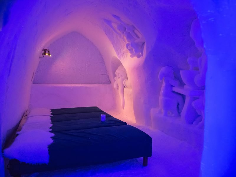 bed in an ice hotel with purple and pink and blue lighting