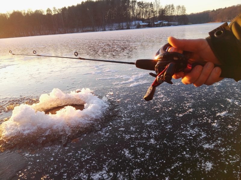 hand holding a fishing pole on a frozen lake