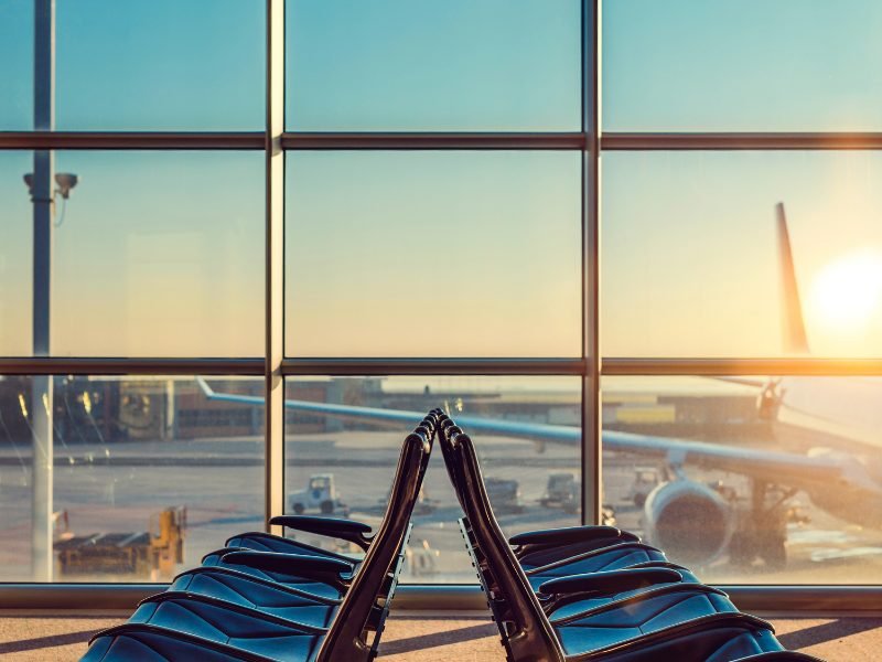 generic photo in an airport of several seats and a plane outside the window