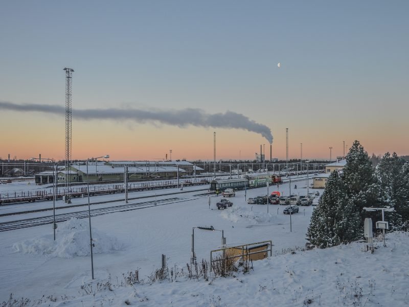 Train station in Rovaniemi Finland with smoke stack and half moon in sky with twilight colors