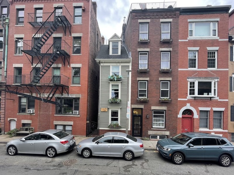 Narrow gray house sandwiched between other larger houses in Boston