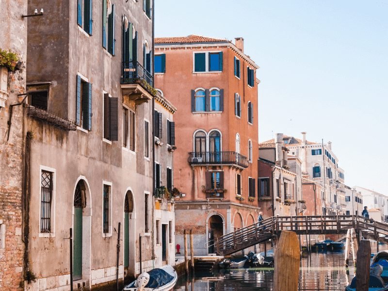 the buildings in the cannaregio area of venice with beautiful bridge and canals and people walking around