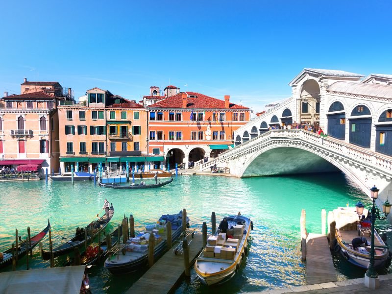 the Rialto bridge in Venice with turquoise canal and gondolas