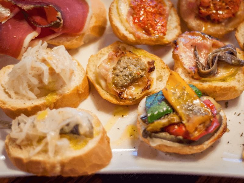 The bar snack of Venice, the cichetti, which involves a bite of food served atop a piece of bread, often served with wine or a spritz before dinner