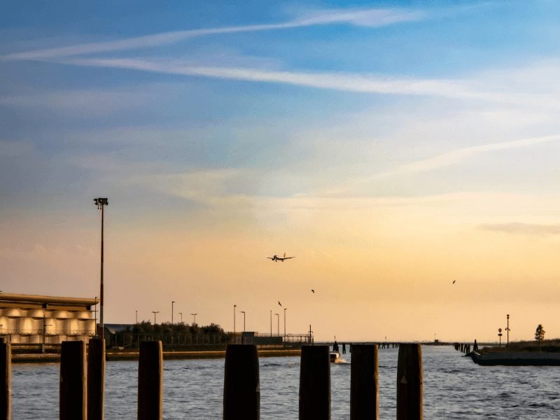 an airplane flying into venice's airport at sunset with a blue and yellow sky