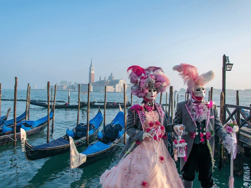 carnival in venice with people dressed up in crazy outfits next to some gondolas