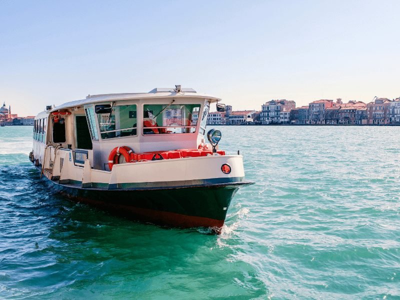 a venice water taxi called a vaporetto on the turquoise water with islets in the background