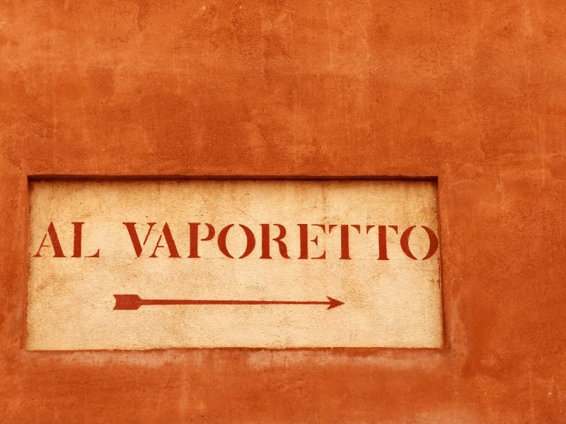 orange wall with sign reading 'al vaporetto' with an arrow