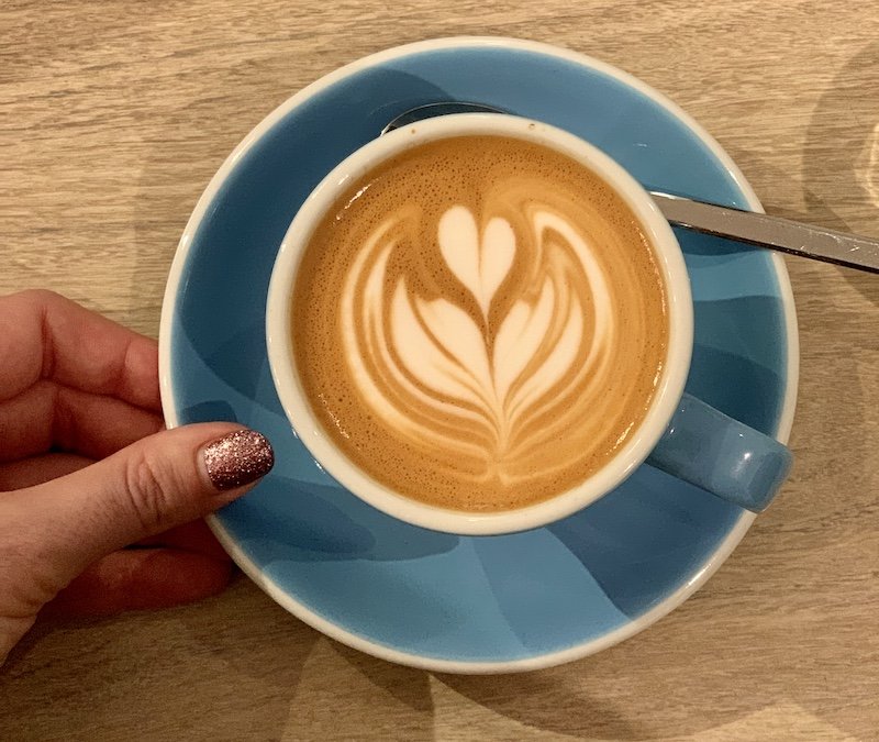 hand with painted fingernails holding a cup of coffee