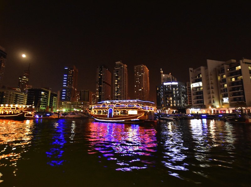 dubai dhow cruise at night with buildings behind it