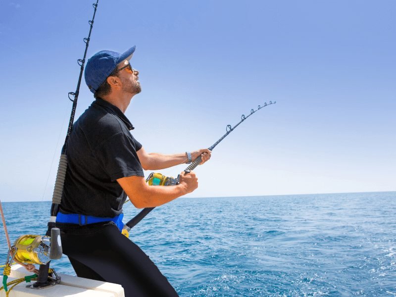 man in a hat fishing off the side of a boat in Dubai