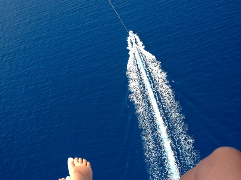 people parasailing in Dubai, looking at their feet above the boat