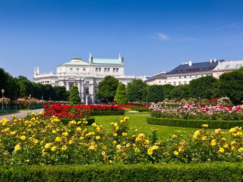 yellow red and pink flowers in the volksgarten with a white building behind it