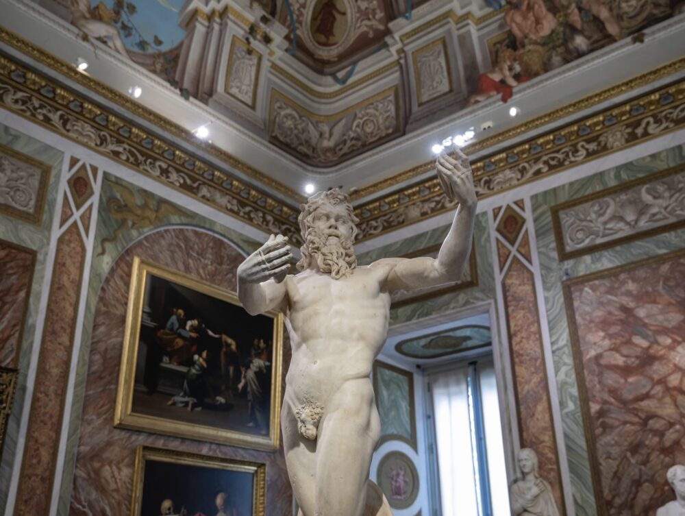 sculpture of a statue with his hands raised in a room full of marble, frescoes, etc in an ornate room of the borghese gallery in rome in winter