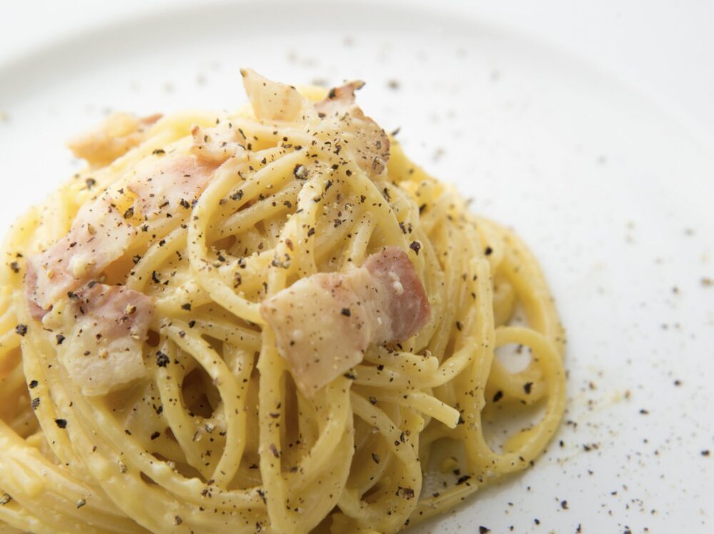 pasta alla carbonara with guanciale, pecorino cheese and black pepper on a white plate