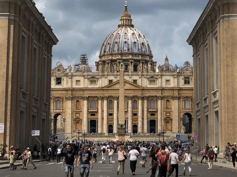 View of St Peters Basilica, one of the most famous Rome landmarks, with an overcast sky and many people in front of the church building