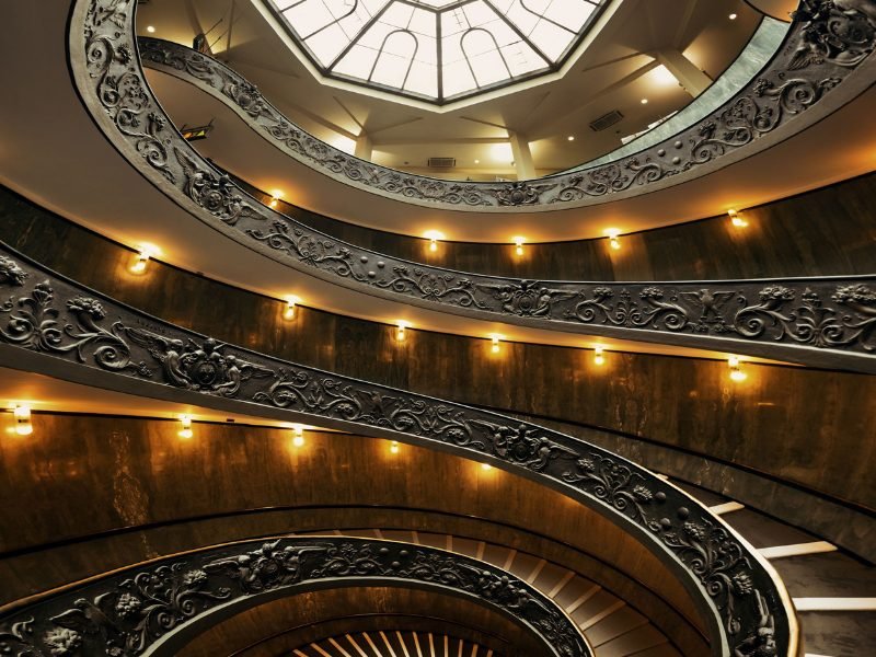 view of the spiral staircase in the vatican museum with lights and skylight