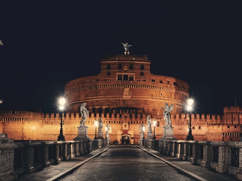 A view of Castel Santangelo in Rome at night, lit up by streetlights