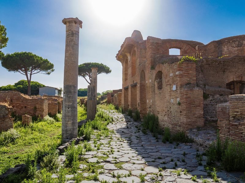 trees and pillar in an ancient old city on a sunny day on a day trip from Rome to the ancient city of Ostia Antica