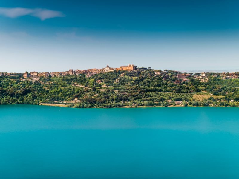 brilliant blue lake with a town on the edge of the lake in castel Gandolfo, a town that makes a great Rome day trip