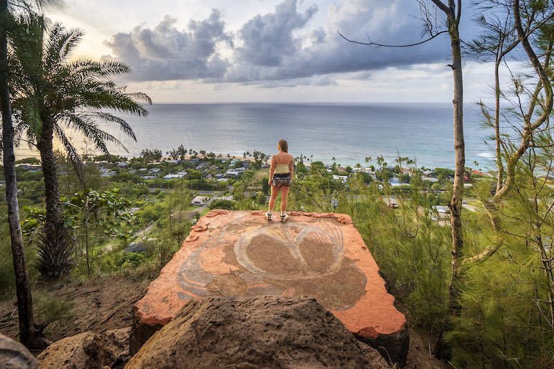 writer atop the pillbox in ehukai looking over the ocean with tropical palm trees and foliage below