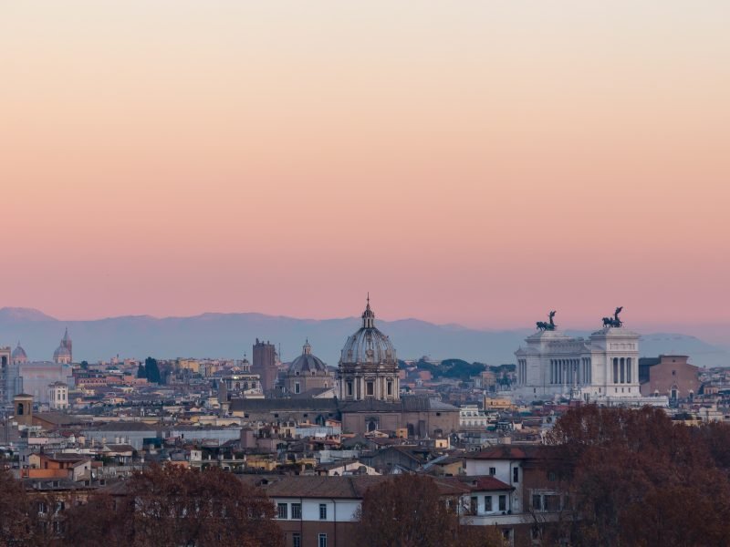 a sunset view with church domes and the altare della patria in rome at night