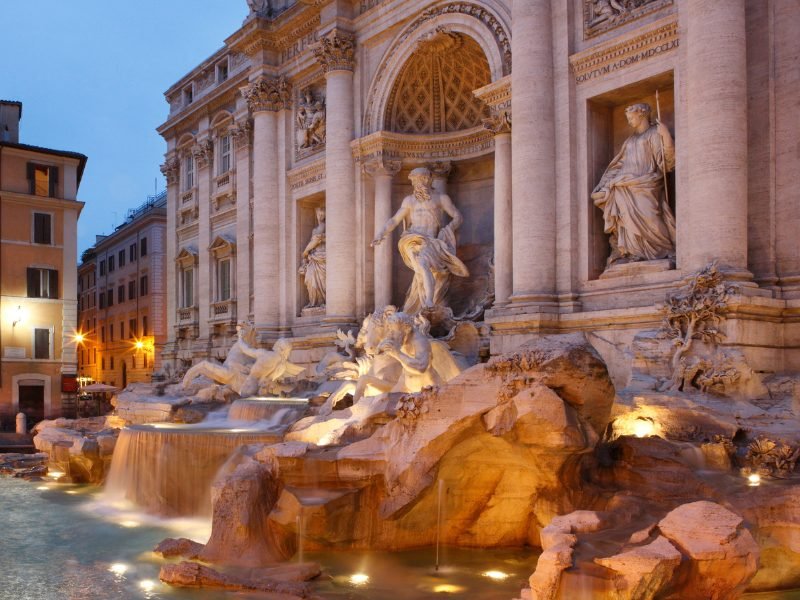 the trevi fountain lit up at night during blue hour at night in rome