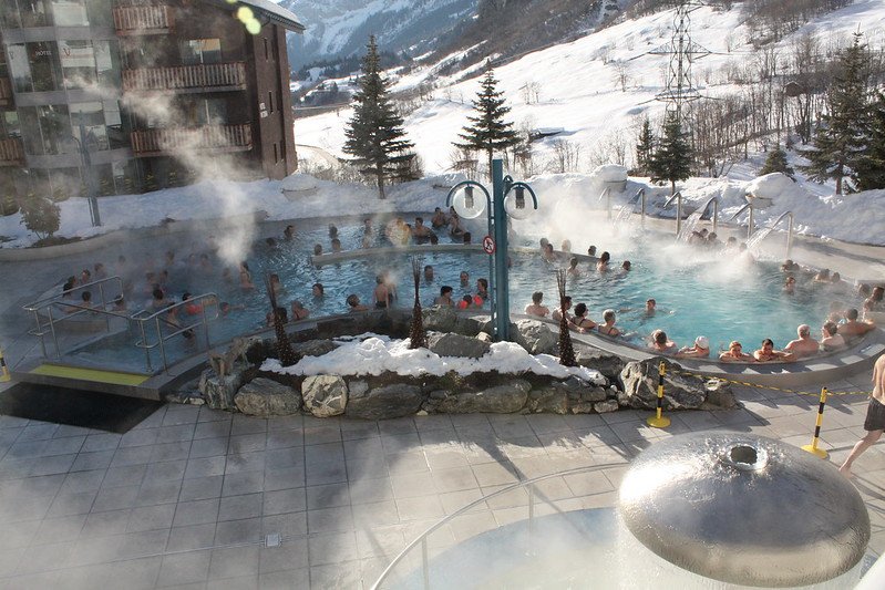 people in a hot thermal bath in the winter with snow outside