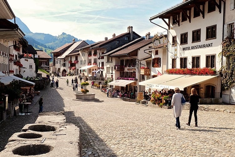people walking around the medieval village of gruyeres switzerland which is famous for its cheese