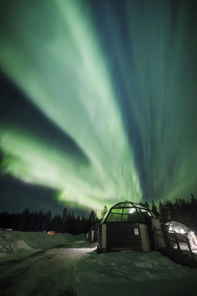 External view of the Northern lights and a glass igloo cabin at this famous glass igloo hotel in Finland.