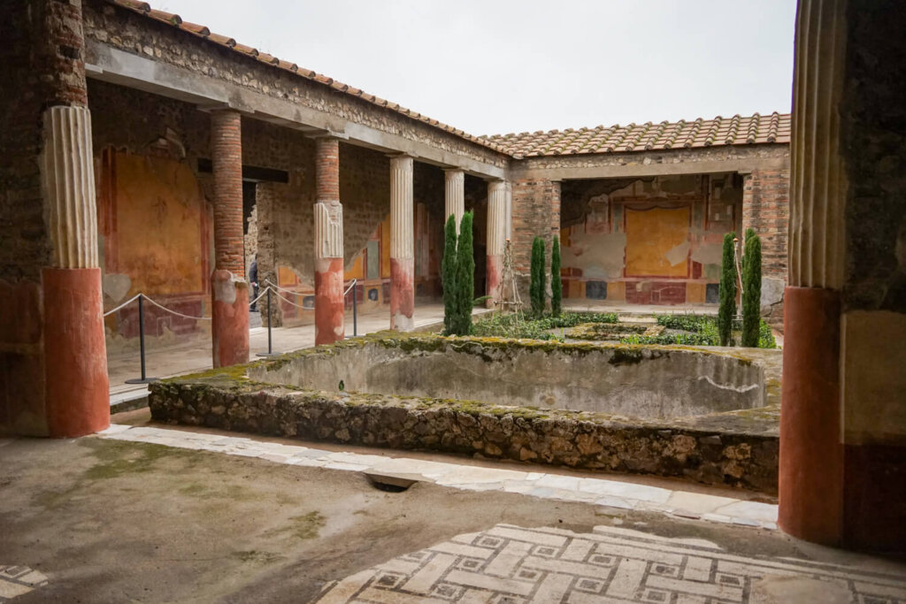 View of one of the many places one would stop on a guided tour of Pompeii, one of the famous courtyards preserved with beautiful mosaics