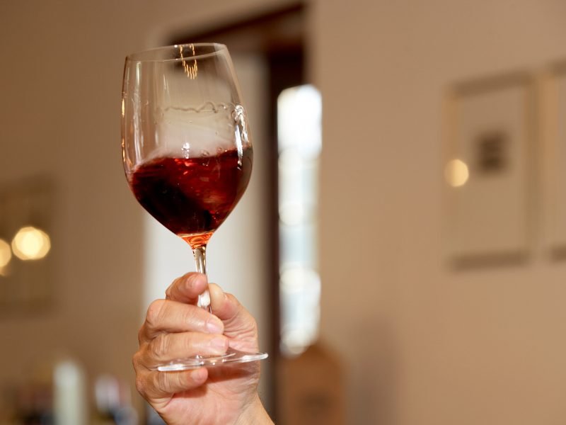 hand swirling a glass of wine in an enoteca in Italy