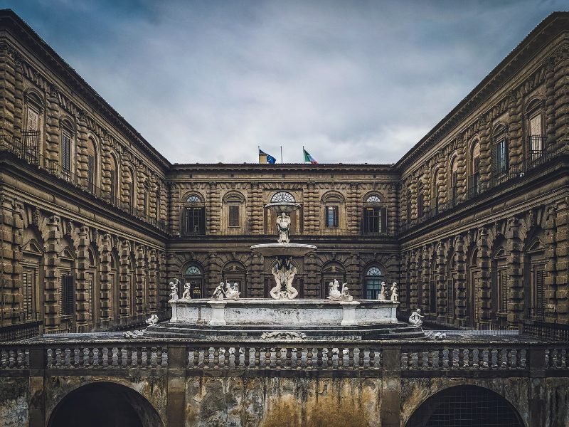 overcast day at Pitti palace in florence Italy in winter with statues and flags and building