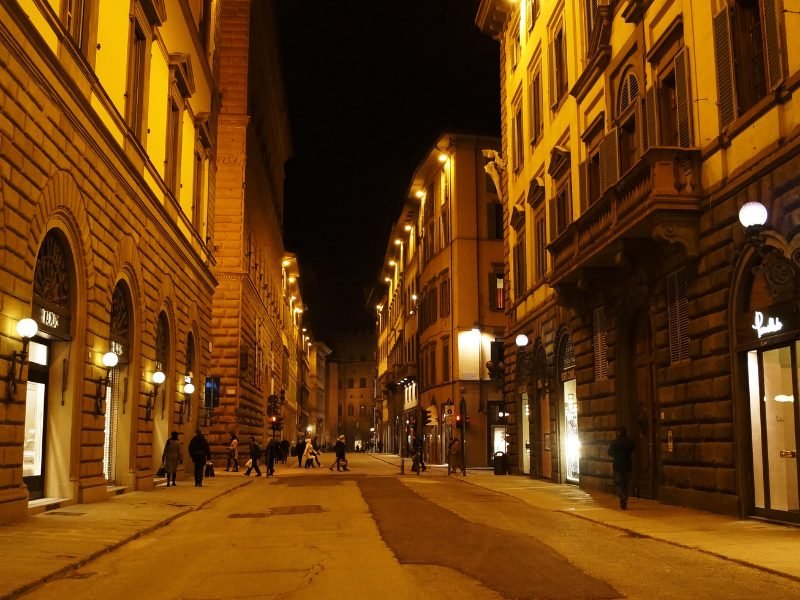 lit up street in Florence in winter with lights and signs on the stores