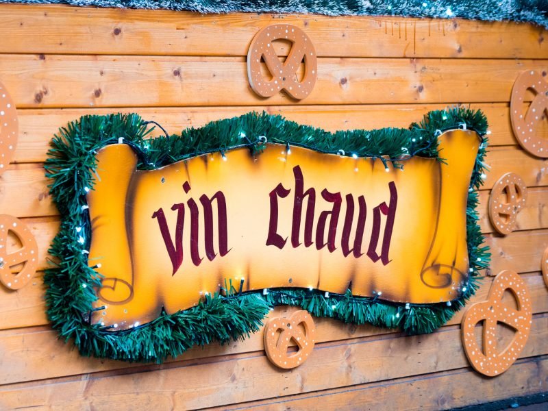 sign with pretzels, faux christmas tree needles that reads 'vin chaud' which means mulled wine in French, at a christmas market in Geneva
