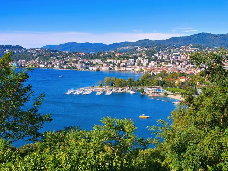 the beautiful lake lugano in southern switzerland with marina, city in background on lake shore