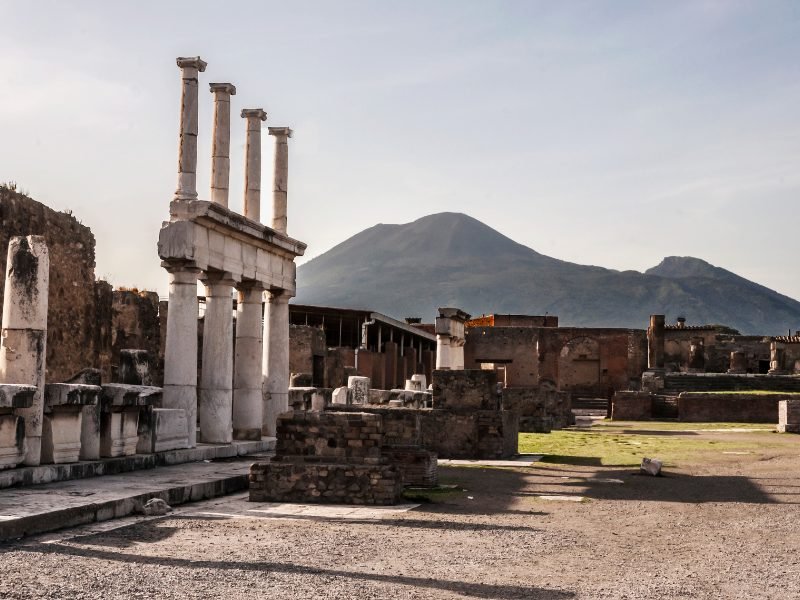 view of pillars casting a shadow in the afternoon light in pompeii with vesuvius in the background